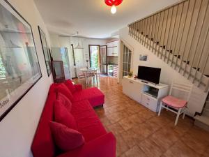 a living room with a red couch and a television at Villa Dosso Fiorito in Lignano Sabbiadoro