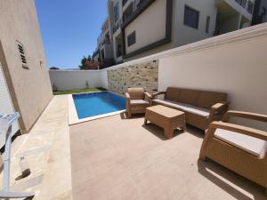 a patio with a couch and chairs and a swimming pool at Luxuary pool appartement in La Marsa