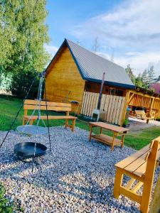 a playground with benches and a swing and a building at Chata z Pary in Giby