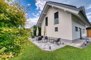 a white house with chairs and a patio at Rooms Minka in Kamna Gorica