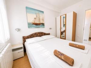 a bedroom with a white bed with a sailboat painting on the wall at Apartments Marija in Senj