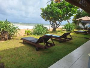 two chairs and a table on the grass near the beach at Ocean Haven in Induruwa