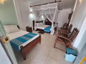 a bedroom with two beds and a chair in it at Ocean Haven in Induruwa