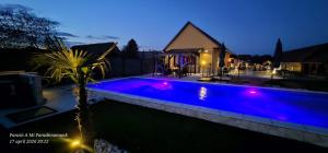 a swimming pool in a backyard at night at Panzio A mi Paradicsomunk in Véménd