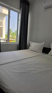 a bedroom with a large white bed with a window at RoaBaa Guesthouse in Batticaloa