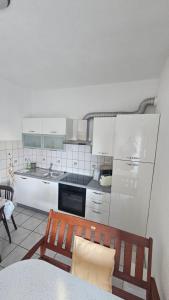 a kitchen with white cabinets and a table and chairs at House Peri in Trogir