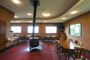 a restaurant with tables and chairs and a wood stove at Saunalodge 白道 in Minami Uonuma