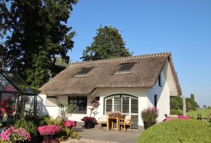 a small white cottage with a thatched roof at Aan de Amstel in De Hoef