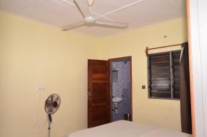a room with a ceiling fan and a bedroom at Résidence Saint Gall-H in Ouidah