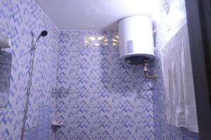 a blue tiled bathroom with a shower with a blow dryer at Résidence Saint Gall-H in Ouidah +7 photos