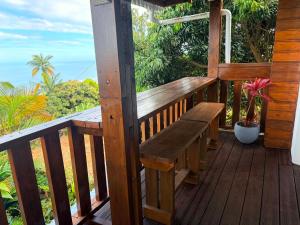 a wooden porch with a bench on a deck at Le petit meublé des hauts in Grande Ravine