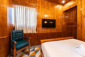 a bedroom with a bed and a chair and a tv at Hotel Palais De Versailles in Pondicherry