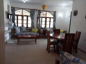 a living room with a couch and a table and chairs at Nelion Villas in Mambrui +16 photos