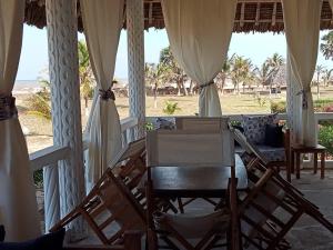 a room with chairs and a table with a view of the beach at Nelion Villas in Mambrui