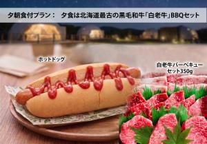 a hot dog on a plate next to some meat at Hotel Asobuba白老 in Shiraoi