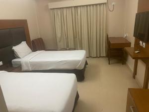 ein Hotelzimmer mit zwei Betten und einem Fernseher in der Unterkunft Hotel Damchen in Phuentsholing