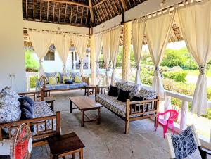 a living room with couches and tables and curtains at Nelion Villas in Mambrui