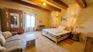 a living room with a bed and a couch at Razzett Pepprina Poppy Farm in Xagħra +26 photos
