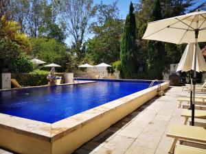 a swimming pool with an umbrella and tables and chairs at La Roulotte in Arles
