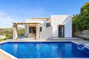 a villa with a swimming pool in front of a house at Villa Ikaros in Agia Triada