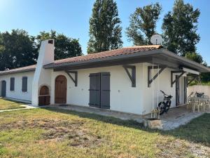 a small white house with a motorcycle parked in front at Maison au calme avec piscine et jardin in BOD