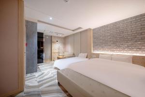 a bedroom with two beds and a brick wall at Hotel Airport in Busan +65 photos