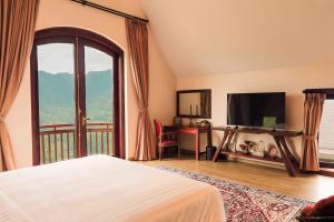 a bedroom with a bed and a tv and a balcony at ALy's Sapa in Tả Van