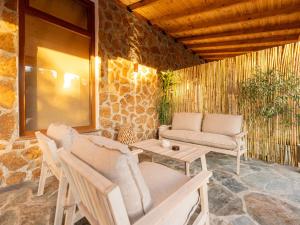 a patio with chairs and a couch and a table at Green Olive Luxury Villas in Paliouri