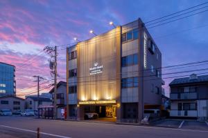 a building on a street with a sunset at WeskiiHotel in Kanazawa