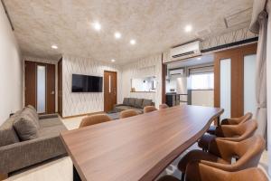a living room with a large wooden table and chairs at WeskiiHotel in Kanazawa