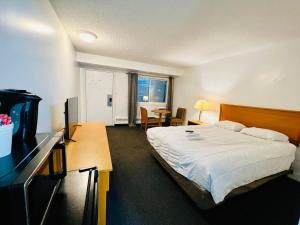 a bedroom with a bed and a desk with a television at Midtown Inn SSK in Saskatoon
