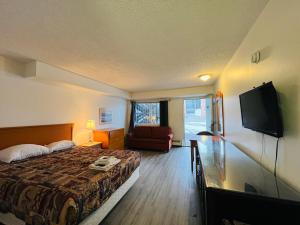 a hotel room with a bed and a tv at Midtown Inn SSK in Saskatoon