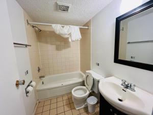 a bathroom with a sink and a toilet and a tub at Midtown Inn SSK in Saskatoon +7 photos