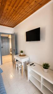 a living room with a table and a tv on the wall at Thelxis Room in Nydri
