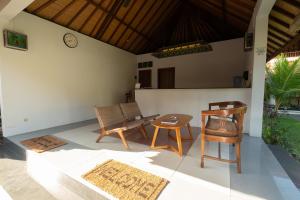 a patio with chairs and a table and a clock at Uns Hotel - Bali in Legian