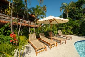 a group of chairs and an umbrella next to a pool at Uns Hotel - Bali in Legian