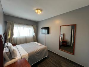 a hotel room with a bed and a mirror at Nduna Legacy Apartment in Harare