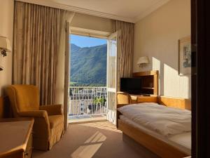 a hotel room with a bed and a chair and a window at Das Alpina in Bad Reichenhall +14 photos