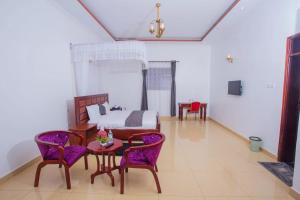 ein Schlafzimmer mit einem Bett, einem Tisch und Stühlen in der Unterkunft FortBreeze Hotel in Fort Portal