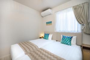 a bedroom with two beds and a window at インギャーラクシー in Miyakojima