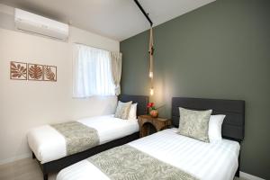 a bedroom with two beds and a window at インギャーラクシー in Miyakojima