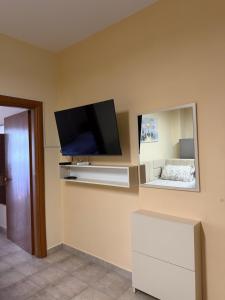 a flat screen tv on a wall with a mirror at Shengjin Central Apartments in Shëngjin +12 photos