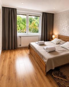 a bedroom with two beds and a large window at Contact Apartman in Bardejov