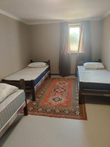 two beds in a room with a rug and a window at Istisu in Müqtǝdir