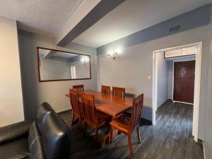 a dining room with a table and chairs and a mirror at Nduna Legacy Apartment in Harare