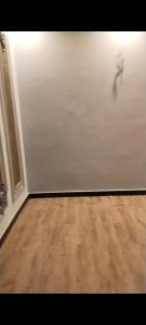 a room with a white wall and a wooden floor at Hayatabad Heights1 in Peshawar +1 photo