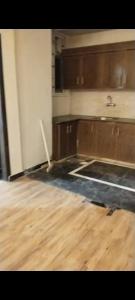 an empty kitchen with wooden cabinets and a wooden floor at Hayatabad Heights1 in Peshawar