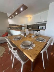 a kitchen with a wooden table with plates and chairs at Ti Repos - Appartement 2/4 pers| Petit-Havre | Parking in Mare Gaillard