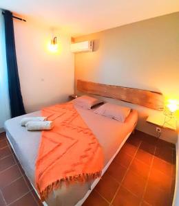 a bedroom with a bed with an orange blanket on it at Ti Repos - Appartement 2/4 pers| Petit-Havre | Parking in Mare Gaillard