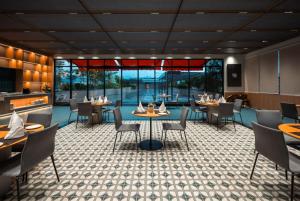 a restaurant with tables and chairs and a large window at The Canvas Loft-Manyata Tech Park-Orchid Parc in Bangalore